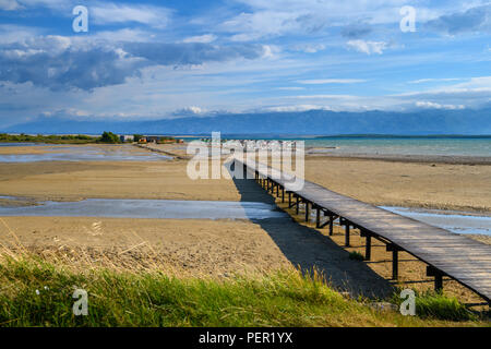 Ein Paar zu Fuß über eine Holzbrücke mit der berühmten Queens Strand in Nin in der Nähe von Zadar, Kroatien. Seltene sand Strand der Adria, beliebt für surfin Stockfoto