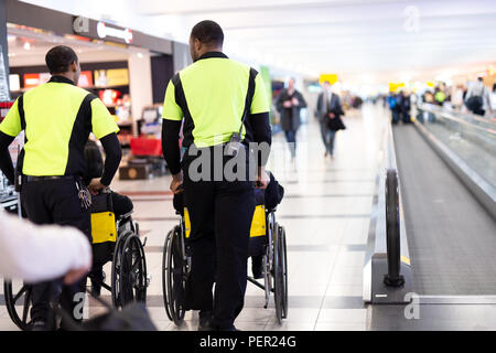 Man Hausmeister drücken ältere Menschen im Rollstuhl im Flughafen. Stockfoto