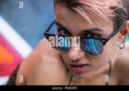 Street Punk oder Hippie Mädchen mit rosa gefärbte Haare. Portrait von Frau mit Piercing in der Nase, Ohren Tunnel und ungewöhnliche Frisur Stockfoto