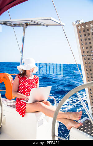 Schöne junge Frau Freiberufler auf ein Segelboot mit einem Laptop. Freiberufliche Arbeit Konzept Stockfoto