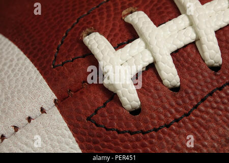 Ein American Football Spiel Ball ist zu sehen in der Nähe, mit dem Blick auf die Schnürsenkel, Heften, und weiß, lackiert Streifen fokussiert. Stockfoto