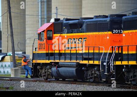 Mendota, Illinois, USA. Ein bremser Herabfallen aus den Schritten einer Lokomotive, während an der äußeren Region ein Güterbahnhof. Stockfoto