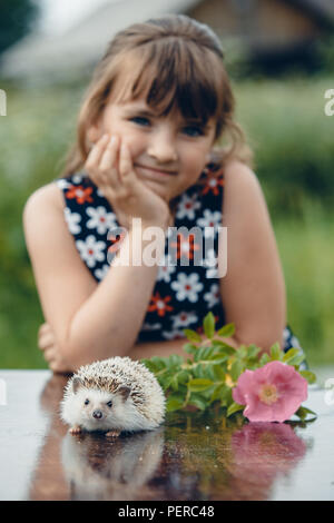 Kleine Mädchen und die stachelige Igel im Sommer am Tisch Stockfoto