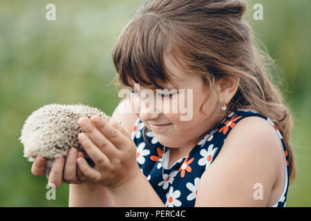 Kleines Mädchen mit einem grauen stachelige Igel in ihre Arme Stockfoto