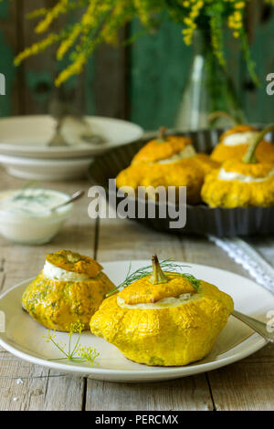 Pattypan Squash oder Kürbisse, gefüllt mit Ricotta mit Basilikum und Dill und serviert mit saurer Sahne Soße. Vegetarisches Essen, rustikaler Stil, selektiven Fokus. Stockfoto
