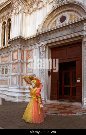 Maskierte Nachtschwärmer in aufwendigen Kostüm und Sonnenschirm außerhalb der Chiesa di San Zaccaria, Castello, Venice, ttaly Stockfoto