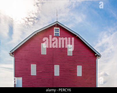 Eine helle rote Scheune auf Ackerland in West Virginia unter der hellen Sonne in einem leicht bewölkt blauen Sommerhimmel Stockfoto