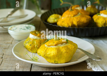 Pattypan Squash oder Kürbisse, gefüllt mit Ricotta mit Basilikum und Dill und serviert mit saurer Sahne Soße. Vegetarisches Essen, rustikaler Stil, selektiven Fokus. Stockfoto