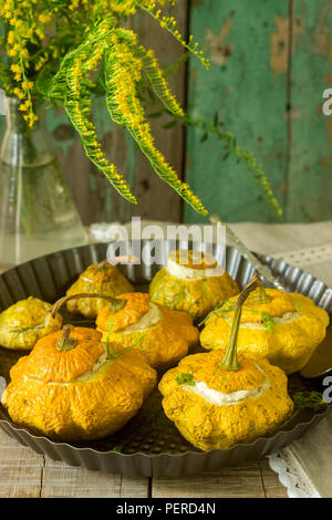 Pattypan Squash oder Kürbisse, gefüllt mit Ricotta mit Basilikum und Dill und serviert mit saurer Sahne Soße. Vegetarisches Essen, rustikaler Stil, selektiven Fokus. Stockfoto