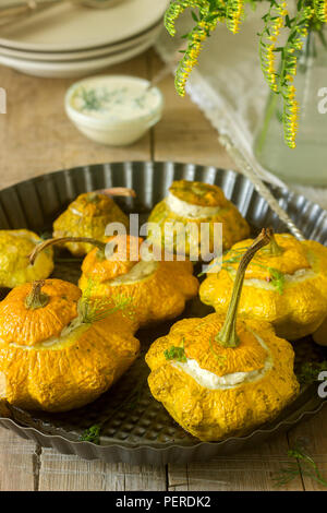 Pattypan Squash oder Kürbisse, gefüllt mit Ricotta mit Basilikum und Dill und serviert mit saurer Sahne Soße. Vegetarisches Essen, rustikaler Stil, selektiven Fokus. Stockfoto