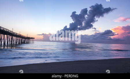 Flache meer Oberfläche reflektiert die verschiedenen Farben des Sonnenaufgangs. Fotos mit langer Belichtungszeit für weiches, verschwimmen mit der Bewegung des Meeres. Dramatischer Himmel und Wolken. Stockfoto