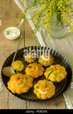 Pattypan Squash oder Kürbisse, gefüllt mit Ricotta mit Basilikum und Dill und serviert mit saurer Sahne Soße. Vegetarisches Essen, rustikaler Stil, selektiven Fokus. Stockfoto