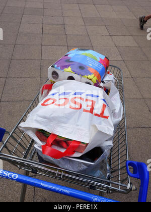 Volle Supermarkt Trolly. Voll mit Lebensmitteln in einem Tesco Beutel gestapelt hoch in einem Tesco Tasche Einkaufswagen über gepflasterte Fläche zum Parkplatz gedrückt wird Stockfoto