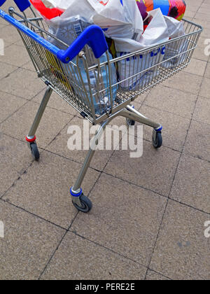 Volle Supermarkt Trolly. Voll mit Lebensmitteln beladen hoch in einem Tesco Einkaufswagen über gepflasterte Fläche zum Parkplatz in Rotherham gedrückt wird Stockfoto