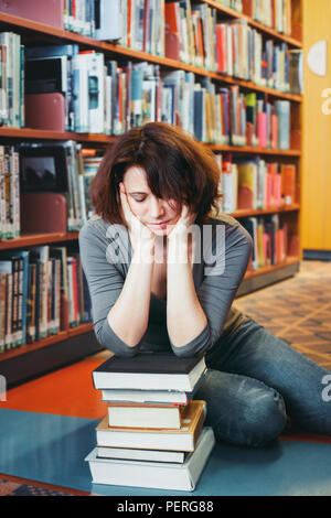 Portrait von müde, mittleres Alter, reife Frau Student in Bibliothek Gesicht sitzen in ihren Armen, Schlafen, Lehrer, Bibliothekar Beruf, zurück in die Schule Konzept Stockfoto