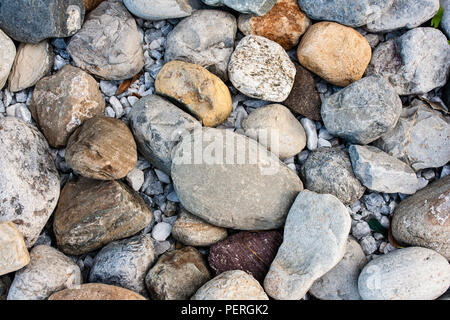 Felsen und Steine am Meer in verschiedenen Formen, Größen und Farben, natürlich angeordnet am Ufer. Stockfoto