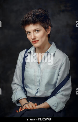 Studio Portrait von schöne nachdenkliche mittleren Alter brunette kaukasische Frau in Kamera schaut. Mädchen mit kurzen jungenhafte Frisur tragen Hemd ein Stockfoto