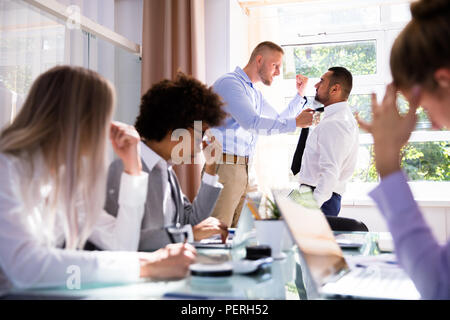 Betonte Geschäftsleute sitzen Vor zwei Kollegen kämpfen im Büro Stockfoto