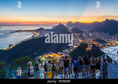 Touristen anzeigen die Christusstatue auf Berg Corcovado und die Stadt bei Sonnenuntergang von Sugarloaf (Pao De Acucar) in Rio de Janeiro, Brasilien Stockfoto