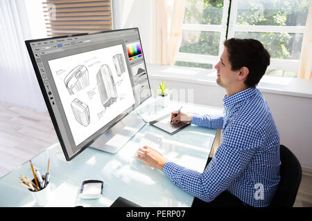 Seitenansicht eines jungen männlichen Designer Zeichnung Koffer auf Computer mit Grafik Tablett Stockfoto