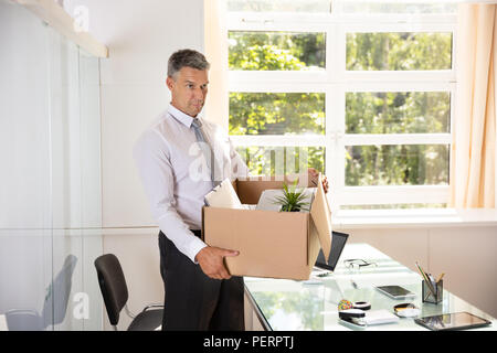 Unglücklich Reife Geschäftsmann, die Sachen in Karton am Arbeitsplatz Stockfoto