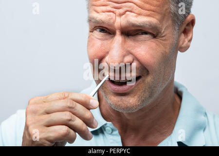 Nahaufnahme einer reifer Mann in den Schmerz Entfernen von Haaren in Nase mit einer Pinzette Stockfoto