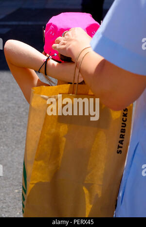 Eine Frau helfen, ihre junge Tochter auf einem rosa Kappe in der Mitte der Sonne in Madrid, Spanien. Stockfoto