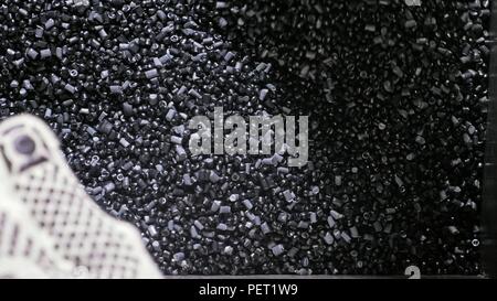 Kunststoff schwarz grau granulierten Crumb. Herstellung von Wasserleitungen aus Kunststoff Fabrik. Prozess, in dem die Kunststoffe an der Werkzeugmaschine mit der Nutzung von Wasser- und Luftdruck. Stockfoto