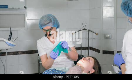 Frau beim Zahnarzt Klinik erhält der zahnmedizinischen Behandlung ein Loch in einen Zahn zu füllen. Zahnersatz und Verbundmaterial Polymerisation mit UV-Licht und Laser. Stockfoto
