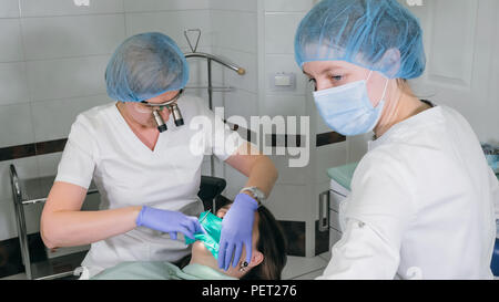 Frau beim Zahnarzt Klinik erhält der zahnmedizinischen Behandlung ein Loch in einen Zahn zu füllen. Zahnersatz und Verbundmaterial Polymerisation mit UV-Licht und Laser. Stockfoto
