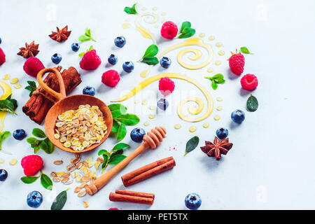 Gesundes Frühstück mit Müsli, Honig, Zimt, Beeren und auf einem weißen Holz- Hintergrund. Kochen Brei flach mit Kopie Raum Stockfoto