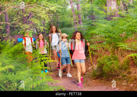 Gruppe von Kindern zu Fuß in den Wald auf die Schule im Sommer eine nach der anderen mit Rucksäcken Stockfoto