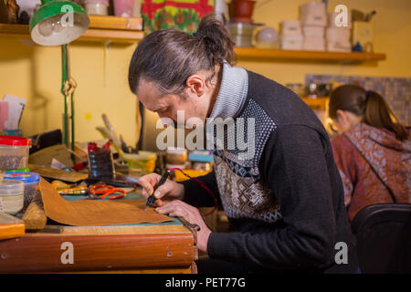 Professionelle männlichen Skinner, Tanner, dekorative Details auf Leder Ausgangsbedingungen für strategisches Brettspiel - tafl mit speziellen pyrographic Maschine Stockfoto
