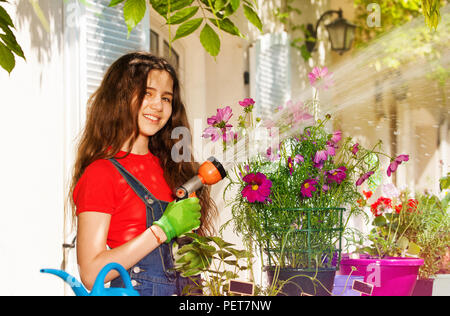 Portrait von schöne Brünette Mädchen Blumen gießen mit Gartenschlauch Stockfoto