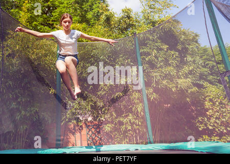 Portrait von Jugendmädchen springen auf dem Trampolin mit Sicherheitsnetz im Hinterhof Stockfoto