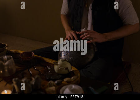 Mann spielt tank Drum oder zu Hause aufhängen. Warme romantische Beleuchtung, Low Key. Entspannung, meditative und traditionelle Musik Konzept. Nahaufnahme Stockfoto