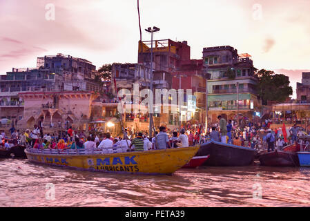 Indianer und Touristen auf Booten in Dashashwamedh Ghat am Abend auf dem Ganges-Fluss in Varanasi, Indien Stockfoto