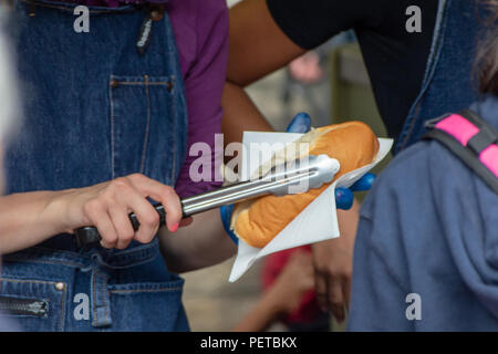 Ein Anbieter bereitet eine Deutsche Hot Dog für einen Kunden in Borough Markt, Southwark, London, UK Stockfoto