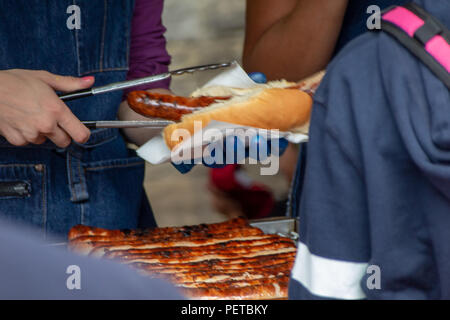 Ein Anbieter bereitet eine Deutsche Hot Dog für einen Kunden in Borough Markt, Southwark, London, UK Stockfoto