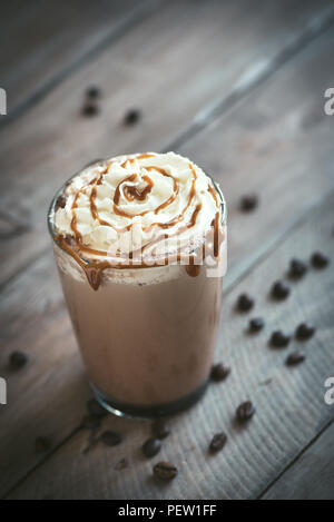 Kalte frappe Kaffee (frappuccino) mit Sahne und Karamell auf dunklem Hintergrund, kopieren. Stockfoto