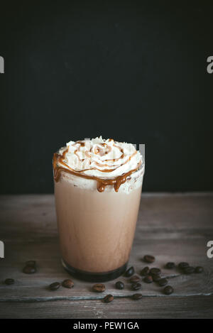 Kalte frappe Kaffee (frappuccino) mit Sahne und Karamell auf dunklem Hintergrund, kopieren. Stockfoto