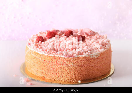 Ein rosa Kuchen mit Baiser bröckelt, Himbeeren, und zuckerhaltigen Rosenblätter. Stockfoto