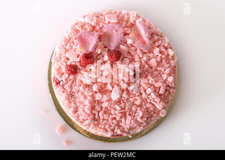 Ein Blick von Oben auf ein rosa Kuchen mit Baiser bröckelt, Himbeeren, und zuckerhaltigen Rosenblätter. Stockfoto