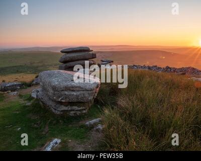 Der Blick auf die untergehende Sonne aus den Steinen der Cheesewring am Bodmin Moor in Cornwall. Stockfoto