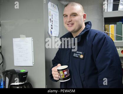 160124-N-KM 956-010 PAZIFISCHEN OZEAN (Jan. 24, 2016) - an Bord der USS John C Stennis (CVN 74). Interieur Kommunikation Elektriker 2. Klasse Brian Guilliams hält eine Tasse Kaffee mit Fotos von seinem 5-jährigen Sohn, Brett. Eine combat ready Kraft kollektiven maritime Interessen zu schützen, USS John C Stennis (CVN 74) arbeitet als Teil der Großen Grüne Flotte in regelmäßigen Western Pacific Bereitstellung. (U.S. Marine Foto von Mass Communication Specialist 3. Klasse Aime Lykins/Freigegeben) Stockfoto
