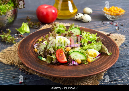 Leckere vegetarische Salat mit frischem Gemüse, Kräuter, Wachteleier, Kichererbsen in einem Ton Schüssel auf einen hölzernen Tisch. Die richtige Ernährung. Gesundes Essen. Stockfoto