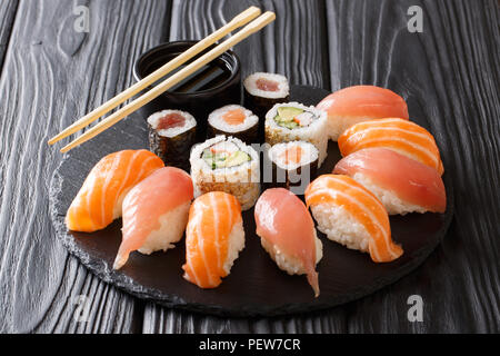 Japanisches Sushi auf einem rustikalen dunklen Hintergrund. Sushi rollen, Nigiri, Maki, Sojasauce. Sushi auf einem Tisch gesetzt. Hintergrund. Asiatische Küche. Horizontale Stockfoto