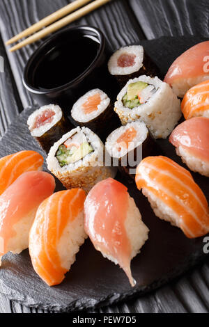 Eingestellt von Sushi mit Lachs und Thunfisch, California Rolls, Maki, Sojasauce closeup auf einem schwarzen Schiefer Board auf dem Tisch. Vertikale Stockfoto