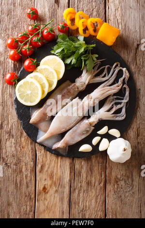 Frischen, rohen Tintenfisch mit Tentakeln closeup und pflanzlichen Zutaten auf den Tisch. Vertikal oben Ansicht von oben Stockfoto