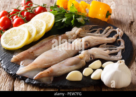 Rohe frische Kalmare close-up und Gemüse zum Kochen auf einer Schiefertafel Board auf einem Tisch. Horizontale Stockfoto